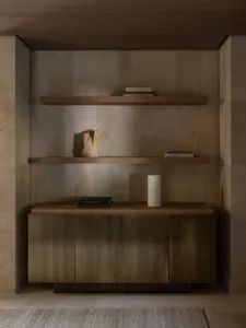 A cozy living space with a wooden bookshelf, books, and decorative items on a tiled floor, lit by soft warm light