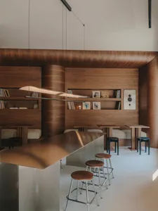 Warm and inviting restaurant with wooden walls, a bar area, and comfortable seating, featuring scattered books and a cozy atmosphere