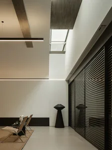 A modern living space with a dining table, chairs, and a vase, surrounded by a large window allowing natural light to enter