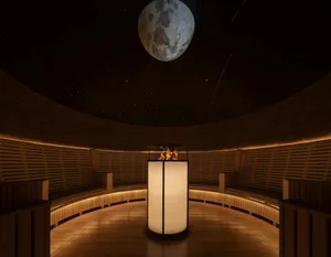 A dimly lit, modern lobby with a large white pillar as the focal point, surrounded by empty space and a predominantly white color scheme
