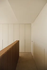 A clean and well-lit white hallway with a brown wooden bench along the wall