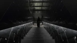 A black and white photograph of a stone staircase with a metal railing in a dimly lit area, captured from the bottom looking up