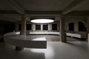A modern kitchen dining space with a white countertop, dining table, chairs, sink, and refrigerator, featuring a predominantly white color scheme and dim lighting