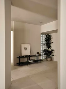 A cozy living room with a black table and a potted plant near a large window, surrounded by a clean and organized space