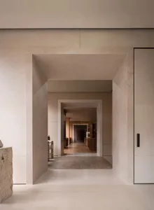 Narrow hallway with white marble floor, white walls, and dim lighting, featuring books on the floor