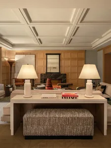 Cozy modern living space with a wooden floor, a fireplace, a couch, and a coffee table, lit by dim lamps and a warm atmosphere