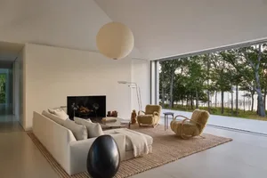 Cozy modern living room with a white couch, a chair, and a fireplace, surrounded by natural light from a large window