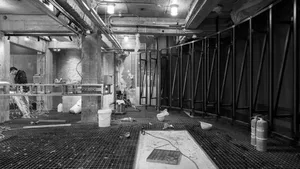 Dimly lit industrial bathroom with two toilets and a cement floor