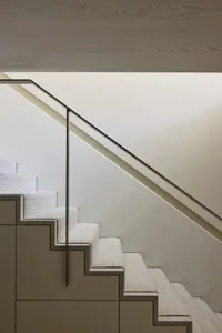 White staircase with a metal railing in a minimalist room with clean lines and a neutral color palette