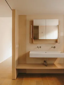 Bathroom with a white sink, large mirror, and wooden walls, featuring soft and diffused lighting