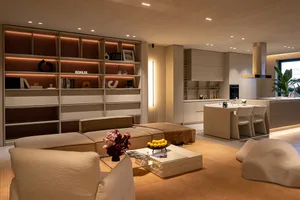 Cozy living room with a large couch, dining table, and kitchen area, featuring modern furniture and decorative vases and bottles, set in a dimly lit space