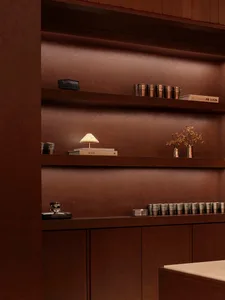 Cozy living space with a wooden shelf and brown wall, featuring various decorative items and a warm atmosphere
