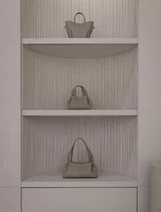 A display case made of wood holds a variety of colorful handbags arranged neatly on shelves in an elegant and sophisticated manner