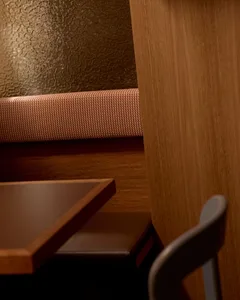 一間餐廳包廂，擺放著一張木桌和棕色的長椅，靠近一面牆壁，前面有一把椅子，在柔和的燈光下營造出舒適的餐廳環境