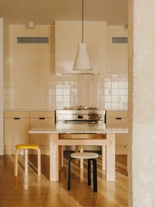 A well-lit kitchen with a dining table, wooden floors, and white tiles, creating a warm and inviting atmosphere