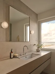 Bathroom with a marble sink, large mirror, and natural light from a window