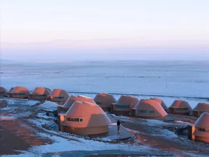 A row of small, round, beige houses made of wood in a snow-covered landscape with a serene and peaceful atmosphere