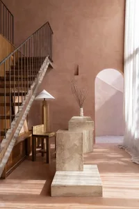 A residential room with a stone floor, wooden railing, and stone wall, featuring a cozy and warm atmosphere with dim lighting