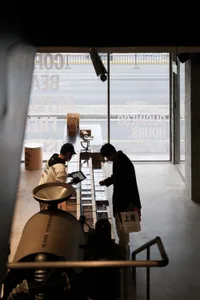 兩名男子站在商店前台前,展示區域、水泥地板和自然光線的窗戶