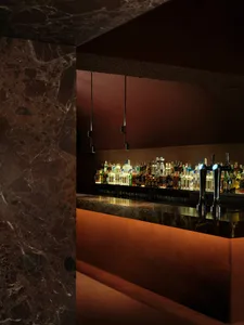 A well-stocked bar with a marble countertop, bottles of liquor, and a sink, creating a cozy atmosphere for socializing and enjoying drinks