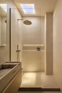 Modern bathroom with a white color scheme, featuring a marble sink, a gold shower head, and a clean, elegant appearance