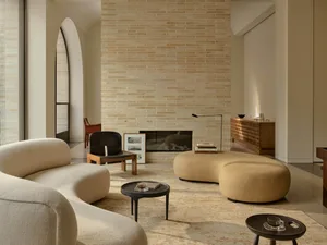 Cozy living room with a brick wall, a couch, a chair, and a coffee table, featuring a modern style with natural materials and a fireplace