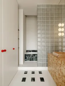A modern bathroom with a black and white diamond-patterned floor, a white door, and a sink and toilet, lit dimly