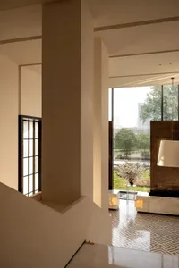 A well-lit living room with a stone staircase, white walls, a couch, chair, and potted plant, creating a welcoming atmosphere