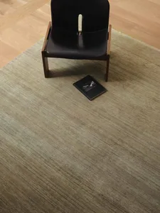 一間舒適的生活空間，裡面有一個黑色椅子，毯子上散落著一本書，給人以放鬆的感覺