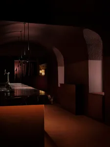 Dark modern bar with a marble counter, brown color scheme, and dim lighting