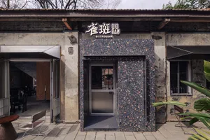 Outdoor restaurant with a stone exterior, a stone wall, and a stone door, set in a natural environment with earthy tones and natural lighting