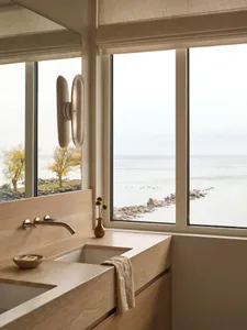 A modern bathroom with a sink on the left and a large window on the right, featuring a clean and organized space with a towel on the window sill