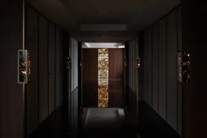 A dimly lit traditional hallway with wooden walls and a carpeted floor, lined with doors