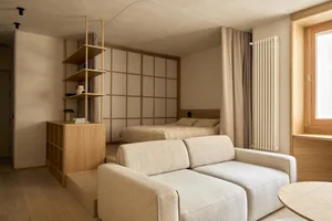 Cozy living room with a beige color scheme, a couch and bed, and natural light from windows