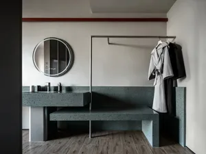 Modern bathroom with a stone bench, mirror, and coat rack, well-lit with clean lines and functionality