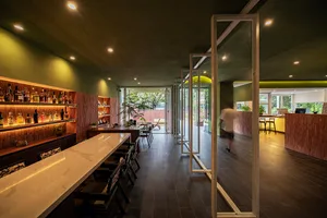 Cozy restaurant with a modern design, featuring a bar area, potted plants, and dim lighting