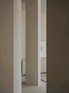 A dimly lit, minimalist hallway with a white door and wall, featuring clean lines and a simple aesthetic