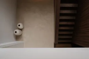 A dimly lit bathroom with two white toilets and a white sink, featuring a minimalist design