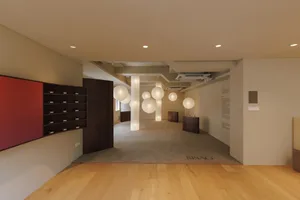A clean and organized lobby with a wooden floor, a large wooden cabinet, a door, and a window, lit by natural light