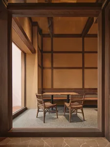 A warm and inviting dining area with a wooden floor, a dining table, chairs, and a bench, lit by natural sunlight