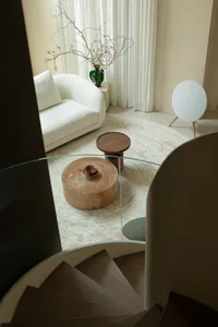 一間光線充足的現代客廳，玻璃餐桌和白色沙發，營造出明亮又溫馨的氛圍