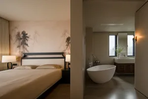 Bedroom with a brown color scheme, Asian-style paintings, a bed against the wall, and a bathtub near the window in a dimly lit space