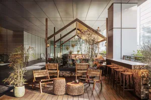 A modern open space with a wooden floor, featuring multiple chairs and dining tables arranged in different positions, creating a welcoming atmosphere for socializing and dining