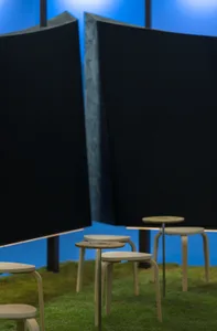A cozy room with a blue wall, black curtain, a table, and several chairs arranged to create a seating area
