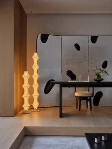 A warm and inviting living space with a wooden floor, a dining table, a couch, and a potted plant, surrounded by chairs and a mirror on the wall