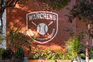 A brick wall with a painted baseball logo, set against a bright and sunny background