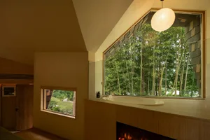 Well-lit bathroom with a wooden design, a large window, a bathtub, and a fireplace, creating a cozy and inviting atmosphere