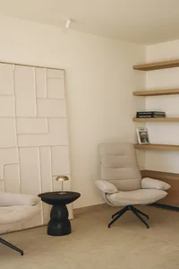 Cozy living space with a white chair, couch, and bookshelf, surrounded by natural light from a window
