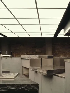 Bathroom with a stone countertop, sink, and shower in a modern style with dim lighting