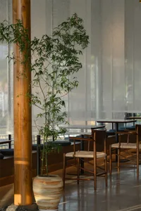 A dimly lit restaurant with wooden floors and furniture, creating a warm and inviting atmosphere with tables and chairs